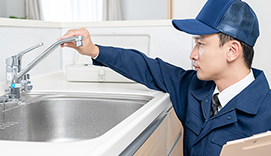 キッチンの蛇口をチェックする作業員の男性